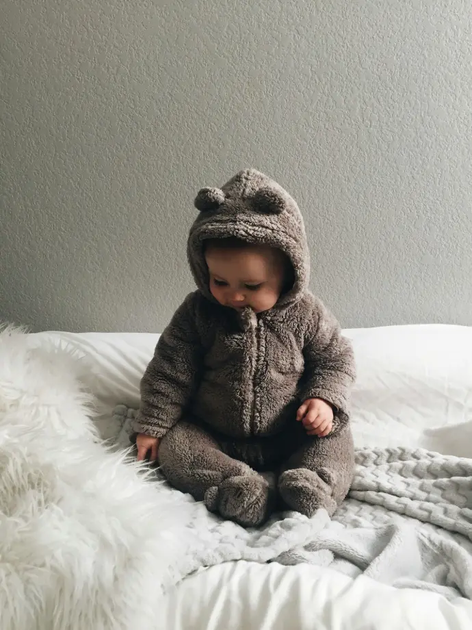 baby seating on white textile